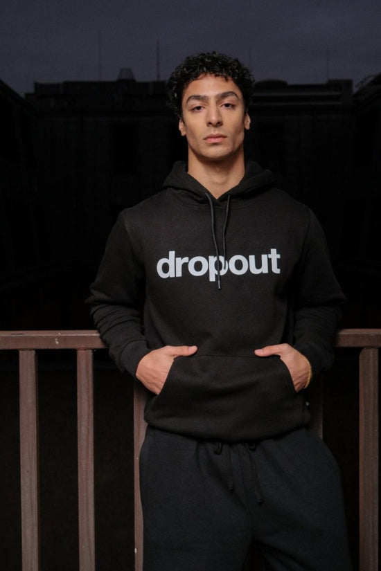 Person wearing a black hoodie with 'dropout' text on a dark background