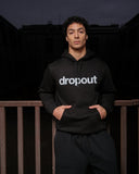 Person wearing a black hoodie with 'dropout' text on a dark background