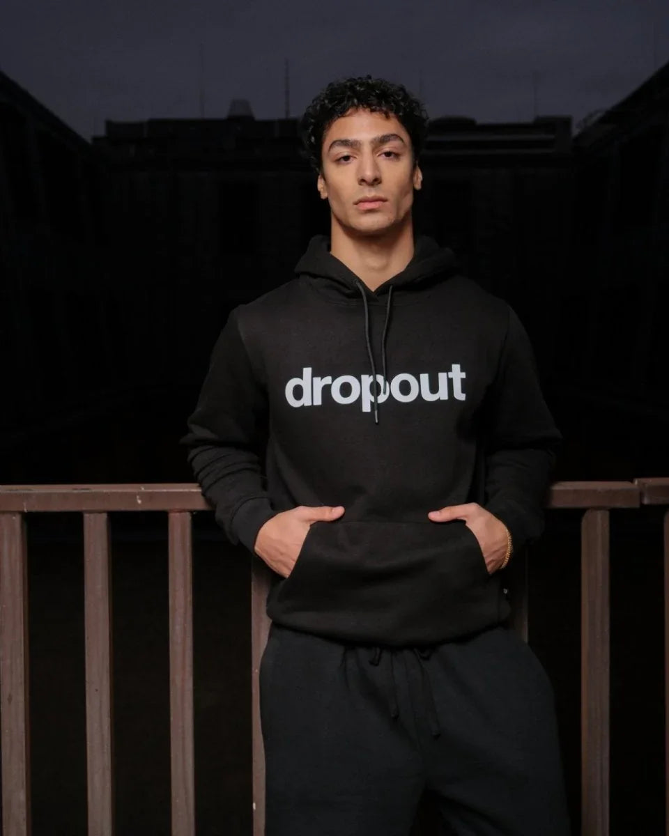Person wearing a black hoodie with 'dropout' text on a dark background