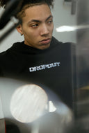 Model wearing black Dropout Chrome hoodie featuring metallic logo detail, showcasing luxury streetwear style.