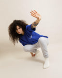 Model wearing blue t-shirt and grey dropout Italics sweatpants, showcasing casual streetwear style.